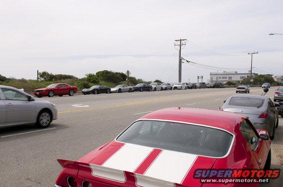 Red car with white stripes parked on the side of the road, rear view