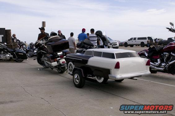 Trailer resembling a 1955 Chevrolet Nomad wagon, two-tone black and white, with whitewall tires, parked outdoors