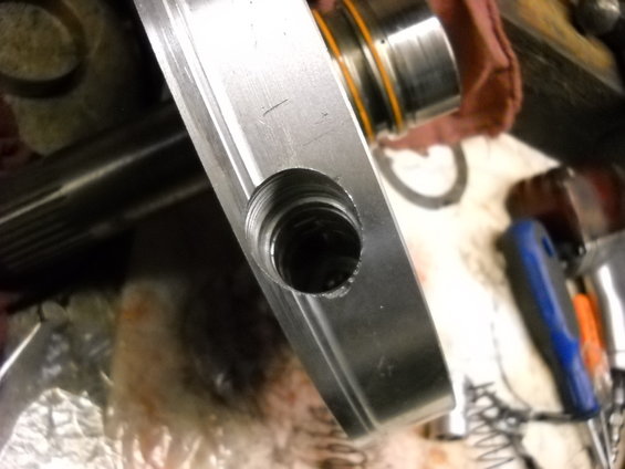 Close-up of a metal part with a threaded hole and visible machining marks