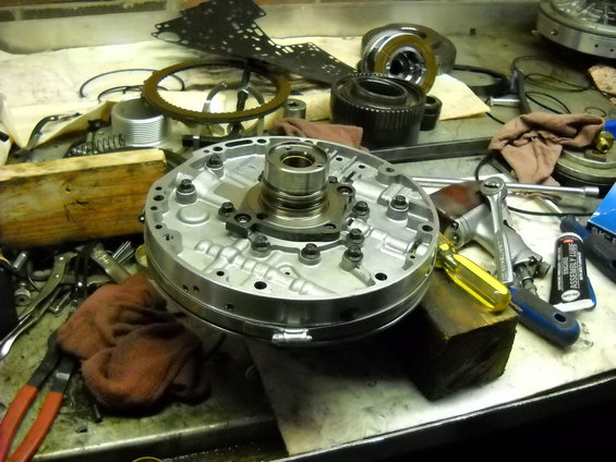 Transmission pump assembly on a workbench with tools and other parts
