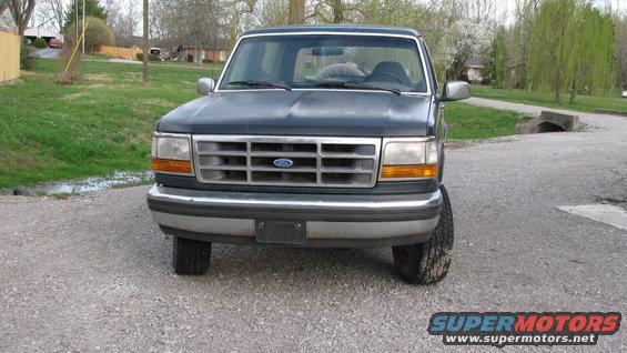 Dark blue 1992 Ford Bronco front view, parked on gravel with a residential background