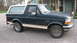 1992 Ford Bronco - This 1992 Ford Bronco is a dark green SUV with a tan stripe and a white removable top.