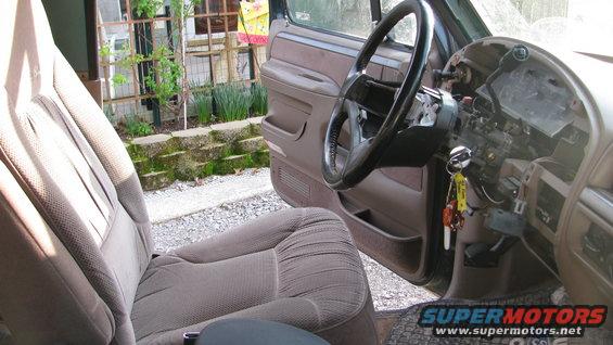 1992 Ford Bronco interior, showing worn brown fabric seats, steering wheel, and dashboard with exposed wiring