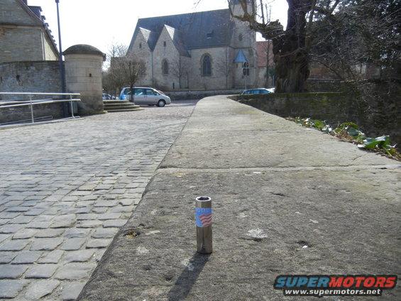 Silver minivan parked on cobblestone street with a church in the background