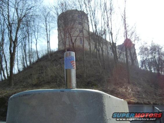 metal pole with a voting sticker on it, in front of a castle on a hill
