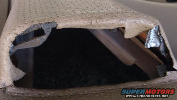 Torn tan perforated upholstery revealing dark interior and foam padding