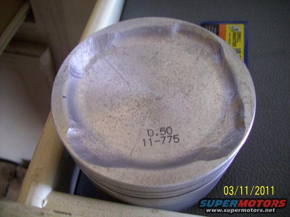 Piston with "0.50 11-775" stamped on it, showing wear marks