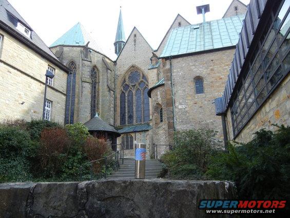 Exterior of a stone church with a spire and large windows
