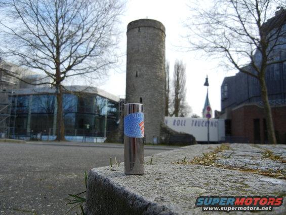Chrome lighter with a 'I VOTE' sticker sits on a stone ledge in front of a tower and modern building