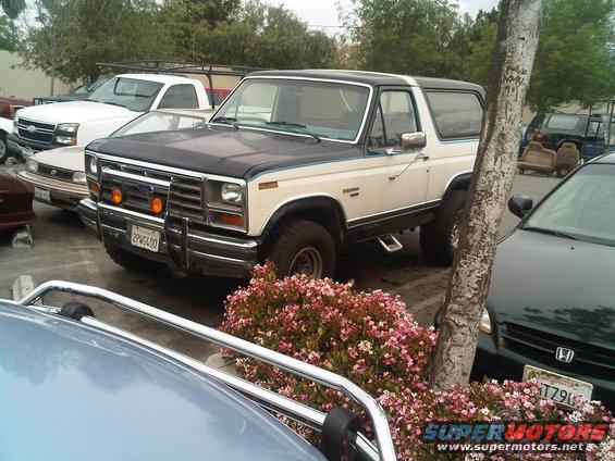 White and black 1980s Ford Bronco with aftermarket bumper and lights