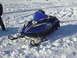 1987 Polaris Indy 600 - A blue Yamaha snowmobile sits on a snowy surface, with a person partially visible on the left.