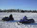 1987 Polaris Indy 600 - A person sits on a snowmobile while another snowmobile is parked nearby on a snowy landscape.