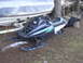 1987 Polaris Indy 600 - A 1987 Polaris Indy 600 snowmobile is parked outdoors next to a boat on a trailer.