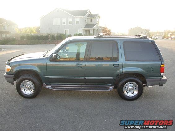 Side view of a green Ford Explorer parked on asphalt with houses in the background