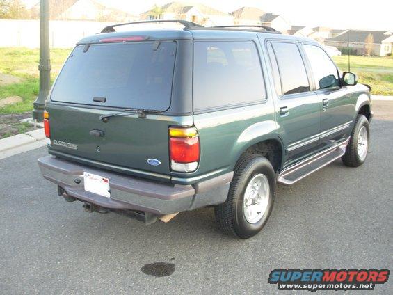 Green 1997 Ford Explorer parked on asphalt, rear view. Has roof rack and running boards