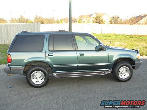 Green SUV parked on asphalt, side view. Visible details include tinted windows, running boards, and alloy wheels