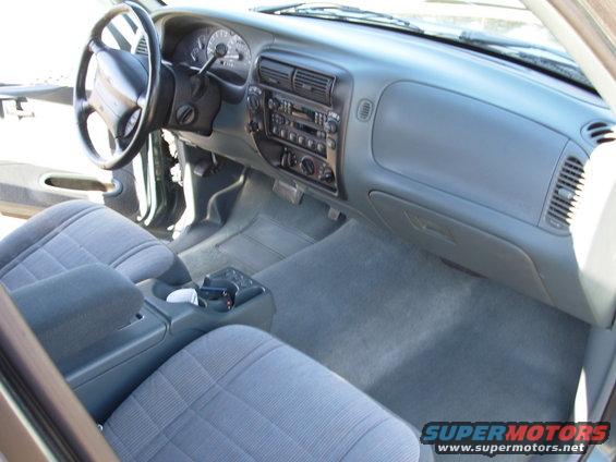 Interior of a 1997 Ford Explorer showing gray cloth seats, dashboard, steering wheel, and center console