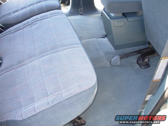 Back seat and center console of a vehicle. The seats are upholstered in a light blue fabric with a striped pattern