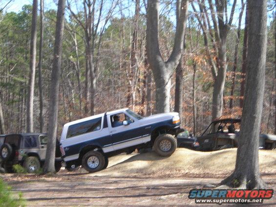 1995 Ford Bronco climbing a dirt hill, with a Jeep Wrangler behind it