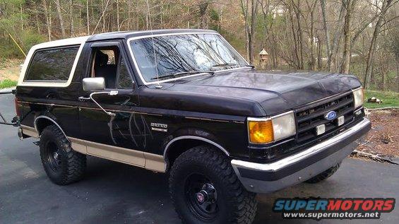 Black Ford Bronco with tan lower trim and white roof. Lifted with off-road tires