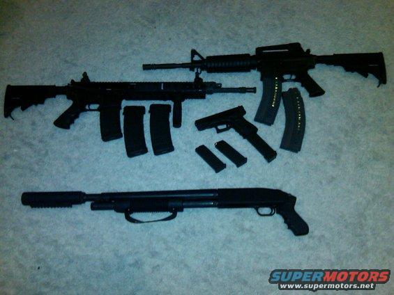 Assortment of firearms and magazines on a carpeted surface