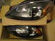 2003 Ford Taurus - Two black headlights for a 2003 Ford Taurus are shown in their packaging.