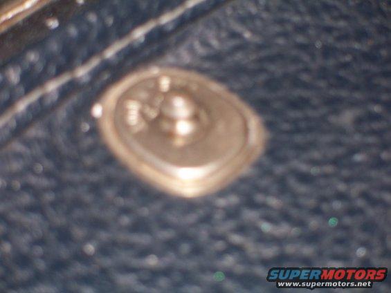 Close-up of a metal snap fastener on a dark, textured surface