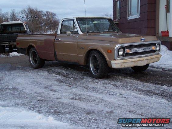 Brown and white pickup truck with a different colored fender, parked on a snowy surface