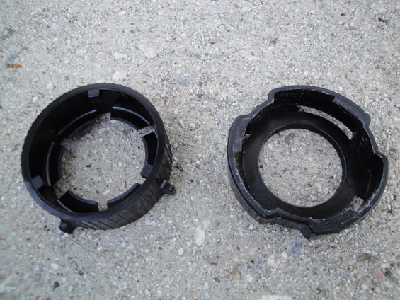 Two black plastic headlight retaining rings on concrete