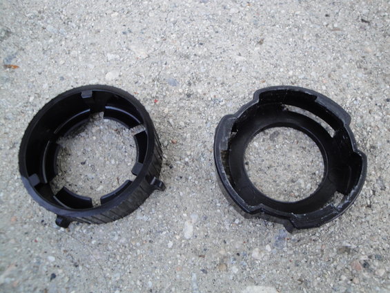 Two black plastic headlight retainer rings on a concrete surface