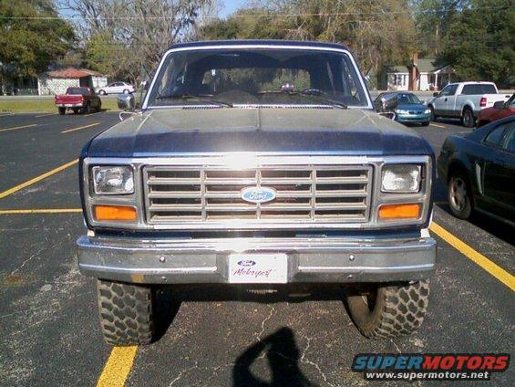 Front view of a blue and gray Ford Bronco with a chrome bumper and off-road tires