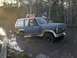 1983 Ford Bronco - Two men are in and around a Ford Bronco that is stuck in muddy water.