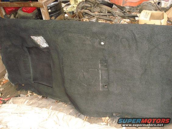 Dark gray carpeted interior panel with two rectangular cutouts, one with a black insert