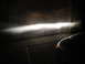 2003 Ford Taurus - Headlight beam projected onto a garage door at night. A car's front corner is visible.
