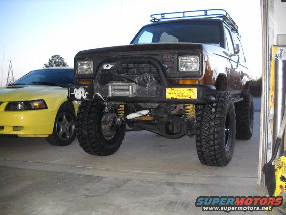1986 Ford Bronco II with winch and roof rack parked next to a yellow Ford Mustang