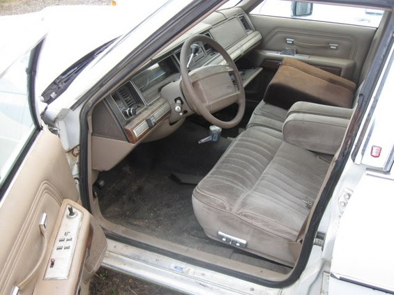 Tan velour interior of a 1990s sedan, showing the dashboard, steering wheel, and front seats