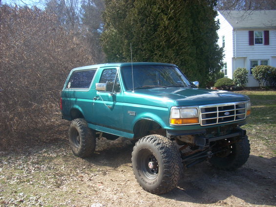 Teal lifted 1996 Ford Bronco with large tires parked outdoors
