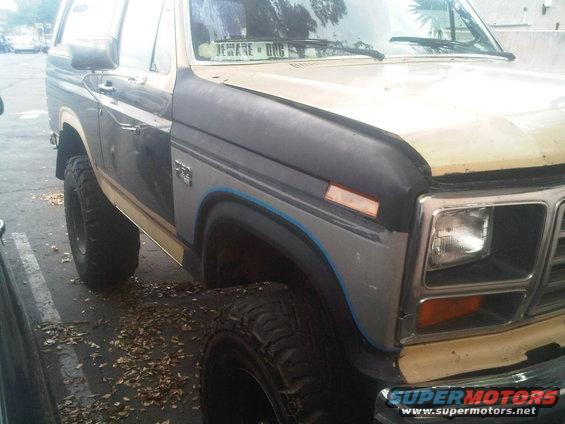 Close-up of a 1980s Ford Bronco's front fender and quarter panel, showing aftermarket modifications and wear
