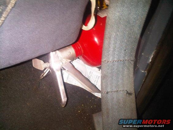 Fire extinguisher mounted on car seat next to seatbelt