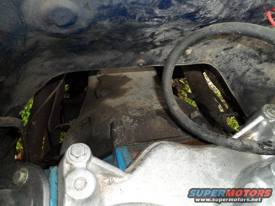 Engine bay with blue and silver components, black hose, and dark metal