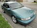2003 Ford Taurus - This teal sedan is parked on the side of a street, showing its front three-quarter view.