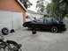 2003 Ford Taurus - A black sedan is parked outside a garage with its hood and trunk open, undergoing maintenance.