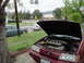 2003 Ford Taurus - A red sedan with its hood open, parked on a residential street next to a chain-link fence.