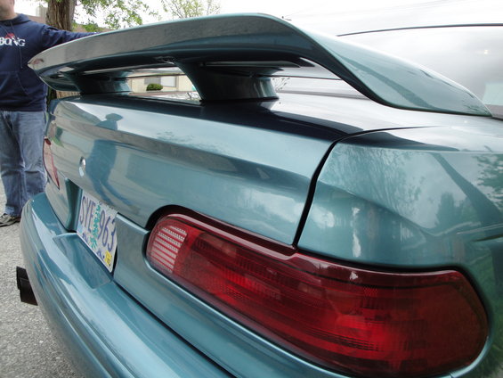 Teal sedan's rear spoiler and taillight. License plate reads SYE 963