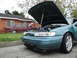 2003 Ford Taurus - Two sedans parked on a street, both with hoods open. One is teal, the other is red.