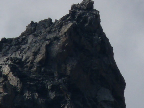 Jagged dark rock formation against a cloudy sky