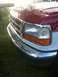 1995 Ford Bronco - Close-up of the front end of a red and white truck, showing the grille and headlights.