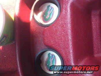 Red dashboard interior with two cup holders, each containing a circular graphic of a green alligator