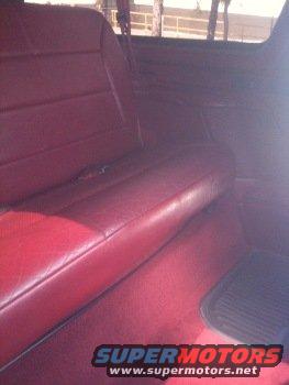 Red leather rear seat and carpeted floor inside a vehicle