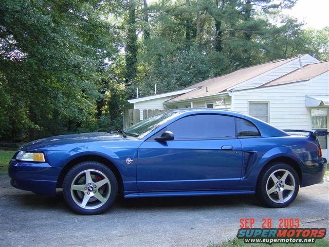 Blue 1999 Ford Mustang coupe parked on driveway, side view